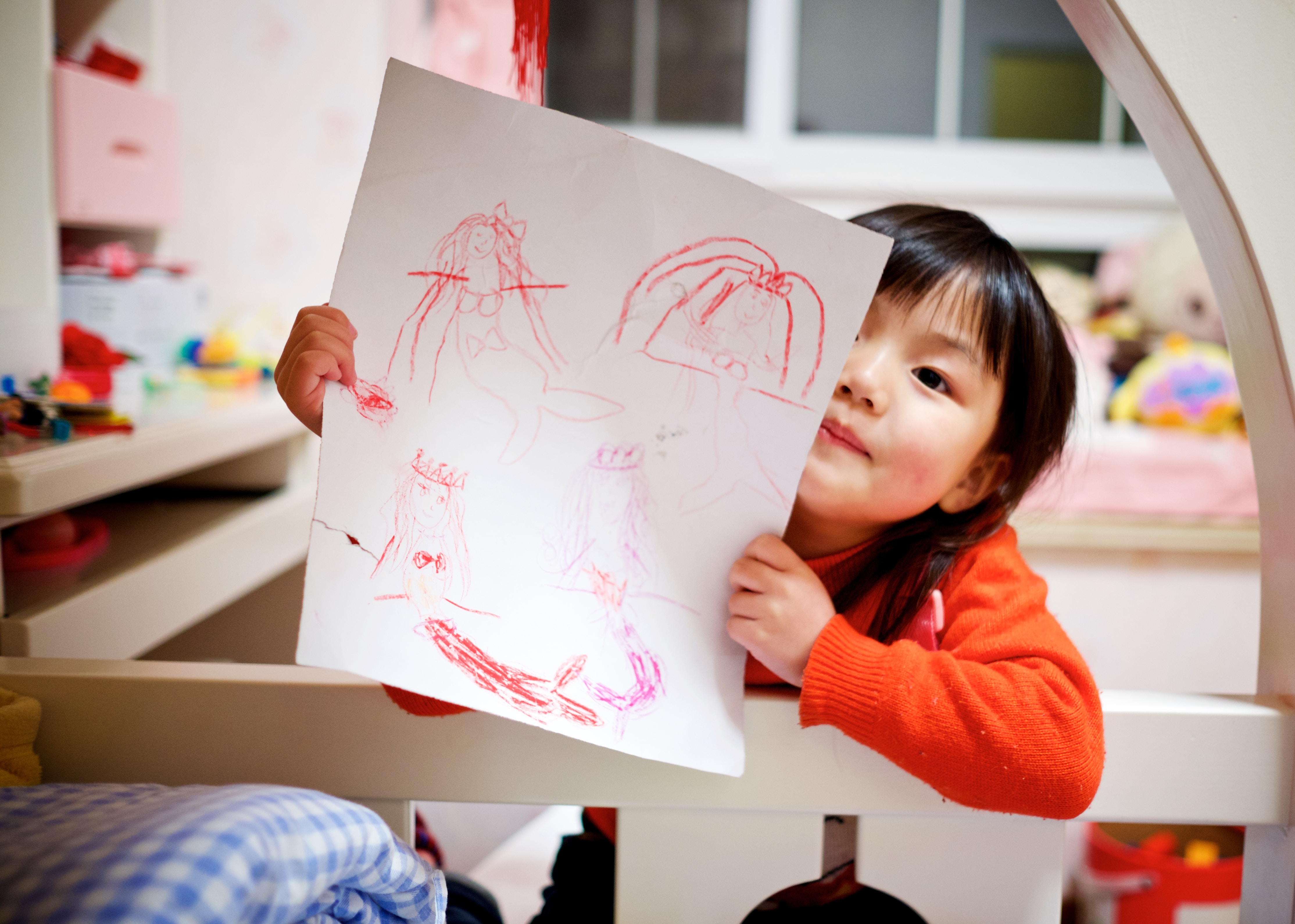 A child proudly holding up a crayon drawing. 