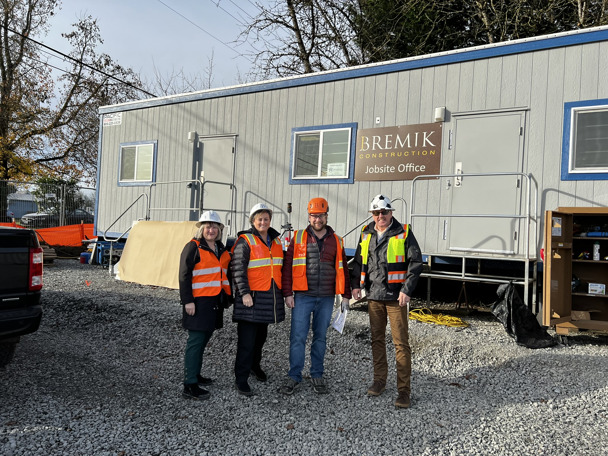Executive Director Jennifer Giltrop and Woodland Community Library Branch Manager Jennifer Hauan stand with workers in front of the Bremik Construction jobsite office 