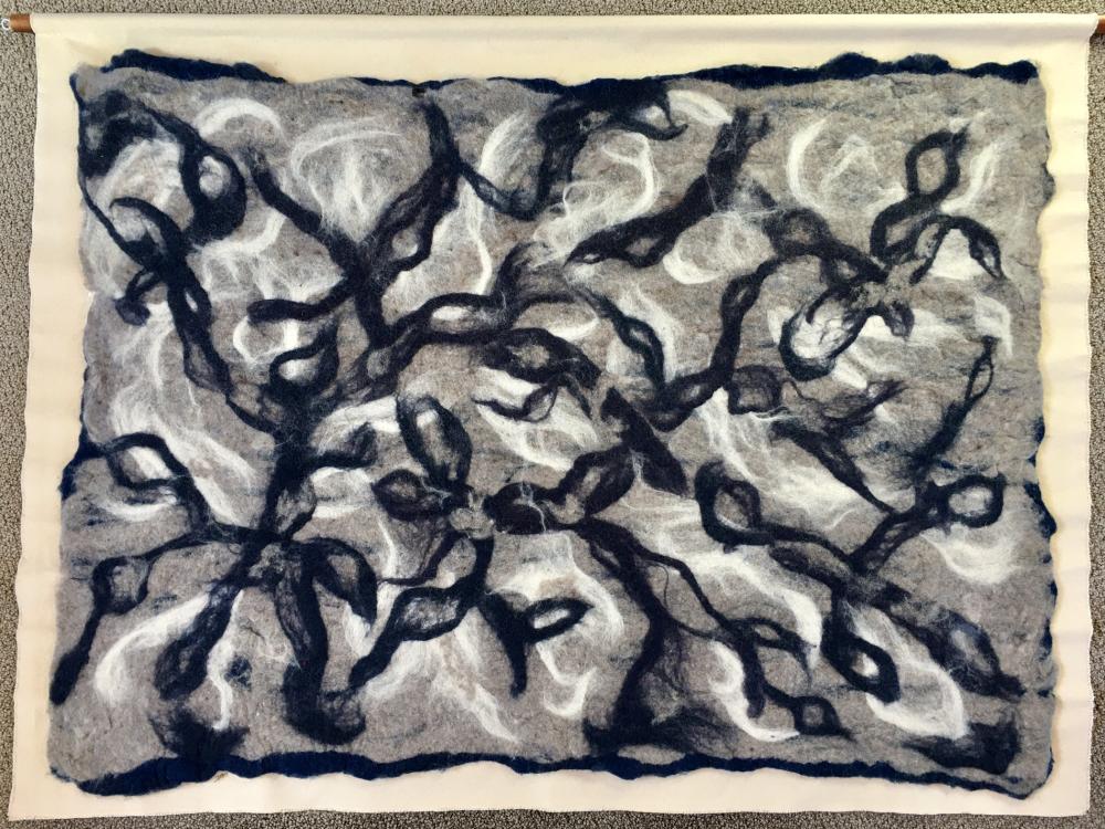 An abstract work of fiber art with black, white, and beige squiggles 