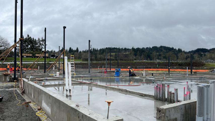 Picture of the freshly poured concrete floor of the future Woodland Community Library, slicked with rain, on a wet day