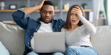 Man and woman looking shocked at computer