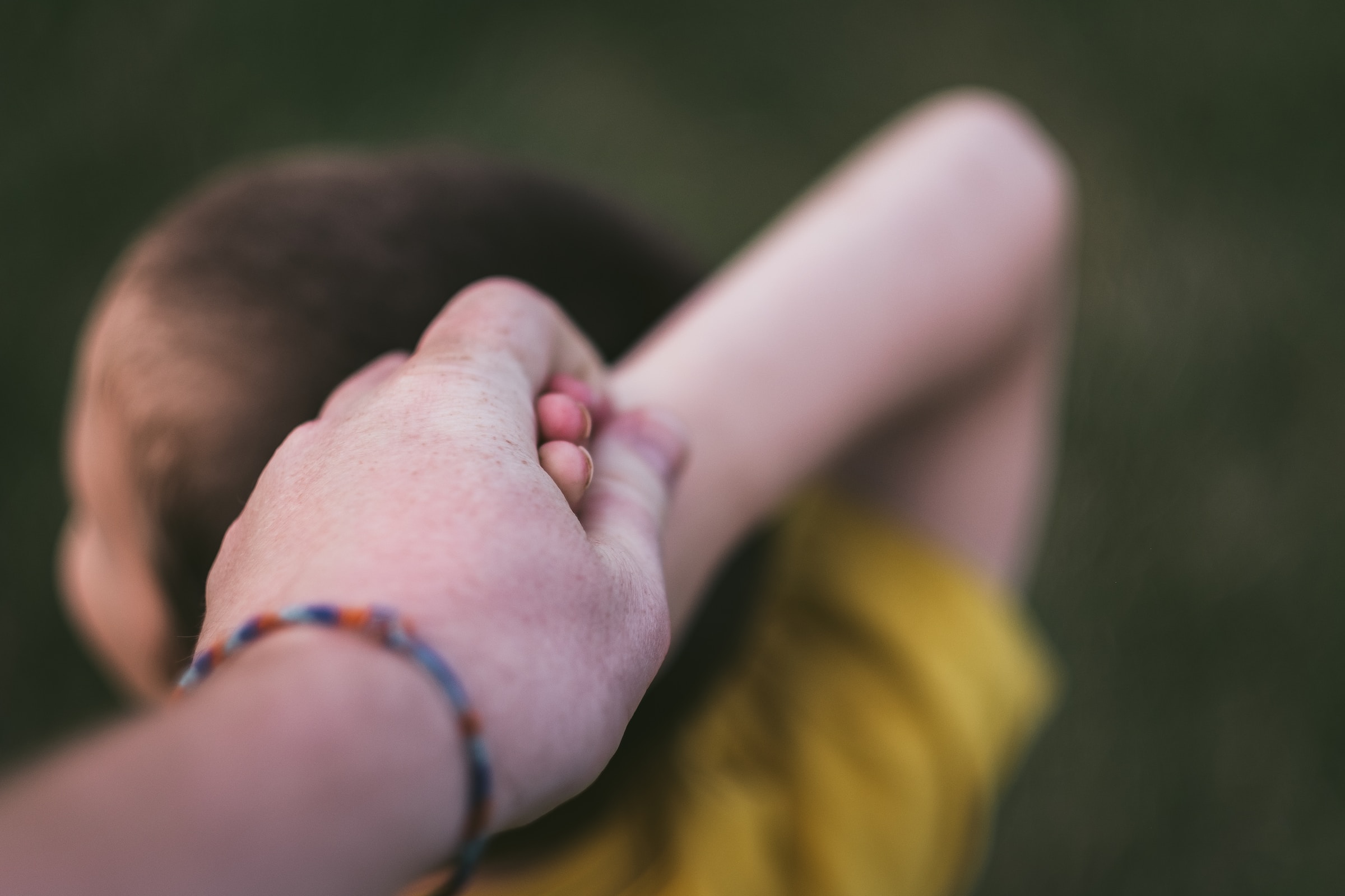 A child holds an adult's hand. 