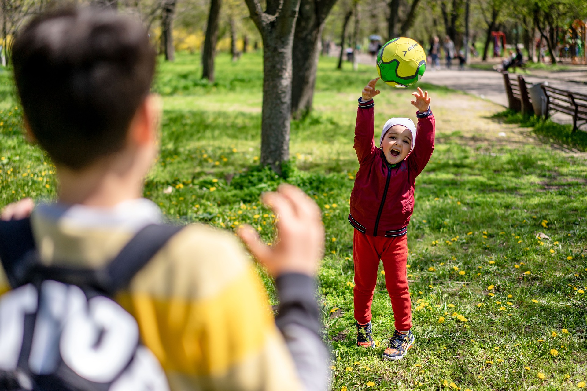 A young child throws a soccer ball to an older child in the park. 