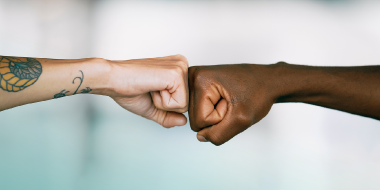 Two arms coming together in a fist bump