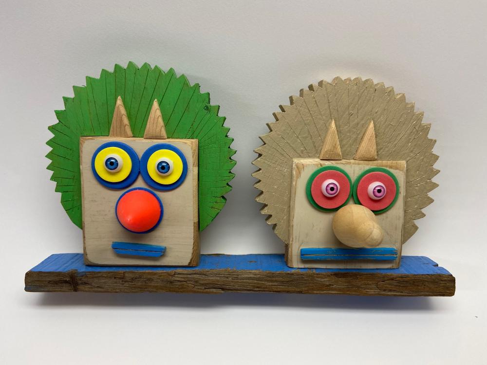 Devil Girl Twins - Rodney Stuart Sculpture of two square faces with pointed ears, long noses, and round eyes.